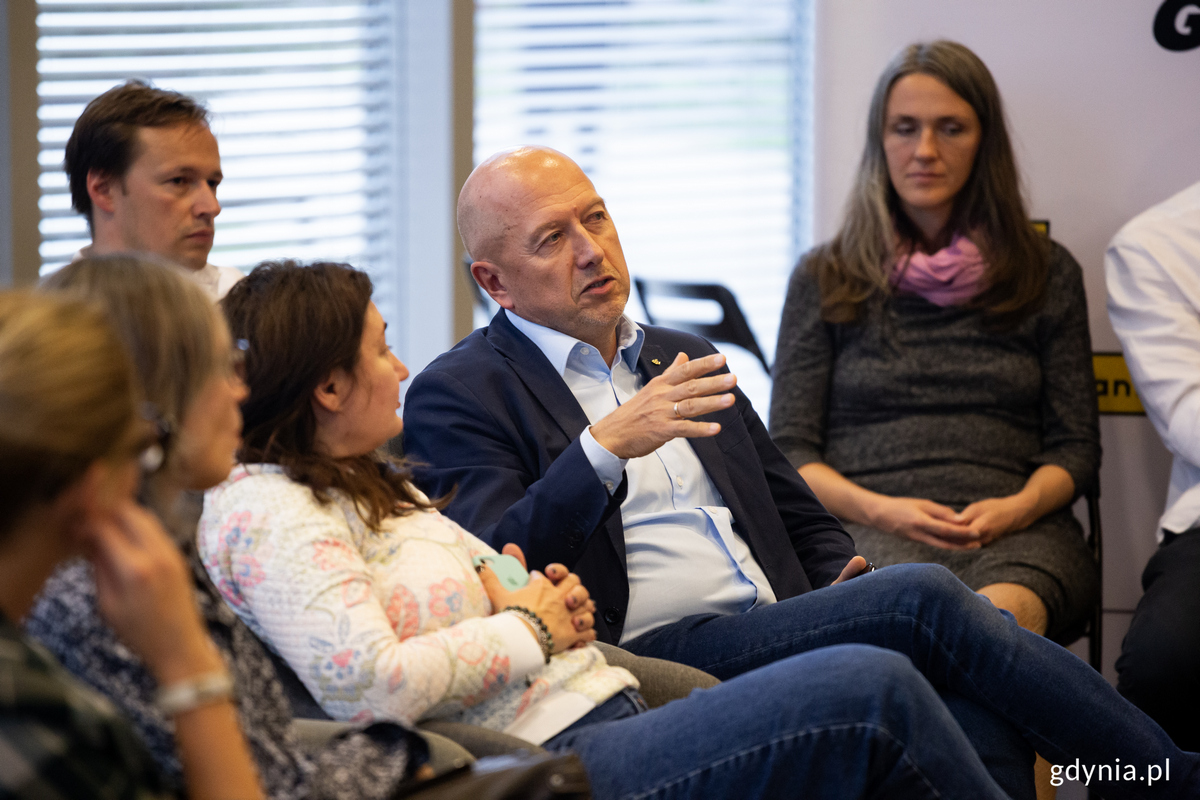 Męzczyzna m&oacute;wi do grupy ludzi w sali seminaryjnej.