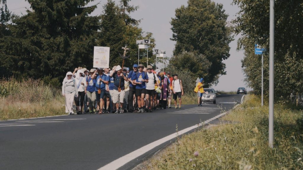 Kadr z filmu "Homo Peregrinus&rdquo;. Na zdjęciu grupa pielgrzym&oacute;w idących ulicą. // Andrzej Święch