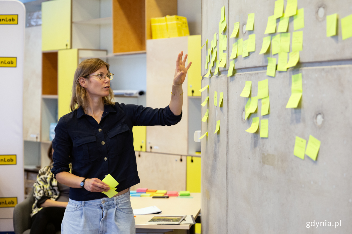 Kobieta przy ścianie z nalepionym kartkami.