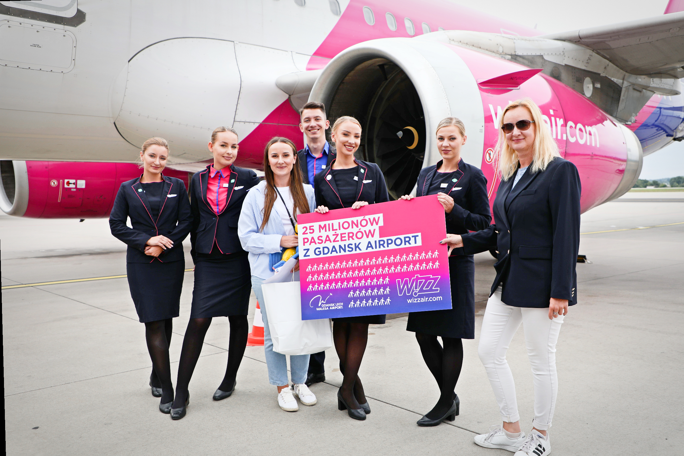 Na płycie lotniska w towarzystwie stewardess stoi 25-milionowa pasażerka Wizz Air