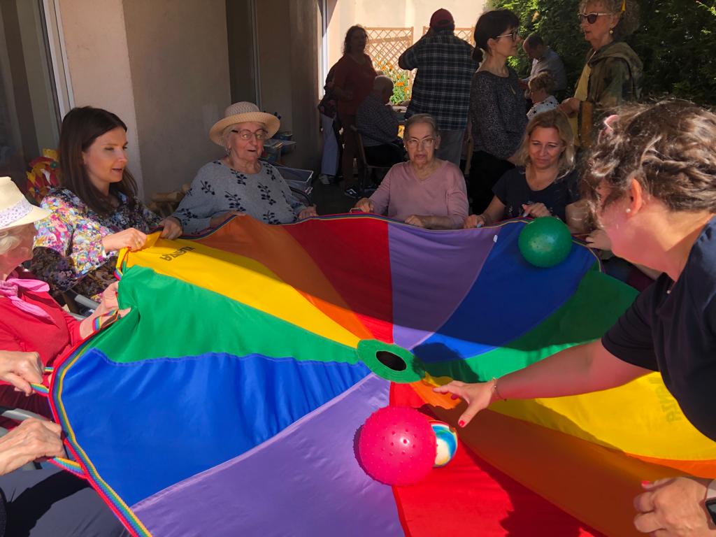 Grupa os&oacute;b w trakcie zabawy chustą animacyjną