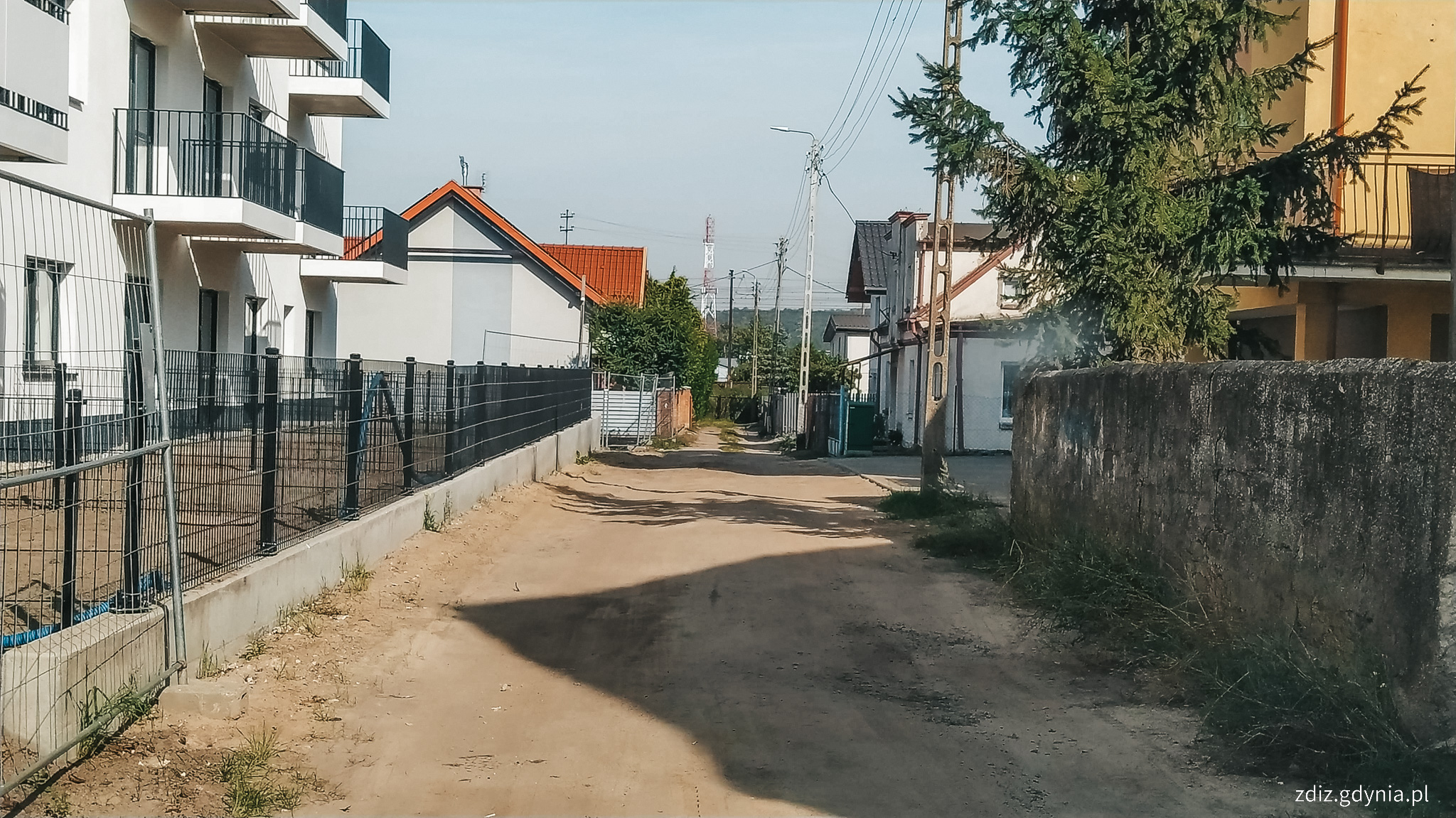 widok na drogę gruntową, w tle budynki