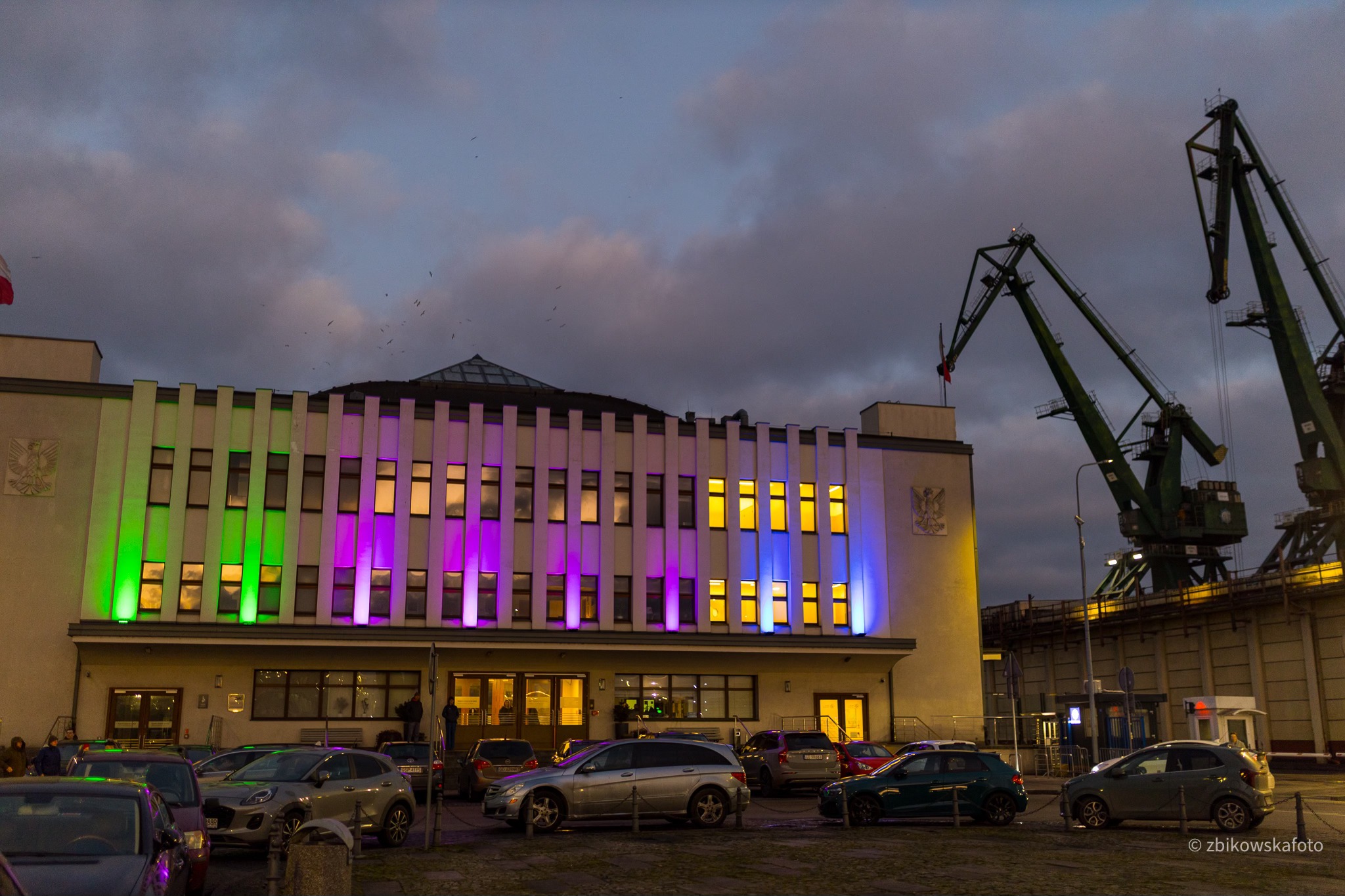 Budynek Muzeum Emigracji, ulica, samochody, wiecz&oacute;r, port, podświetlona elewacja kolorowymi światłami