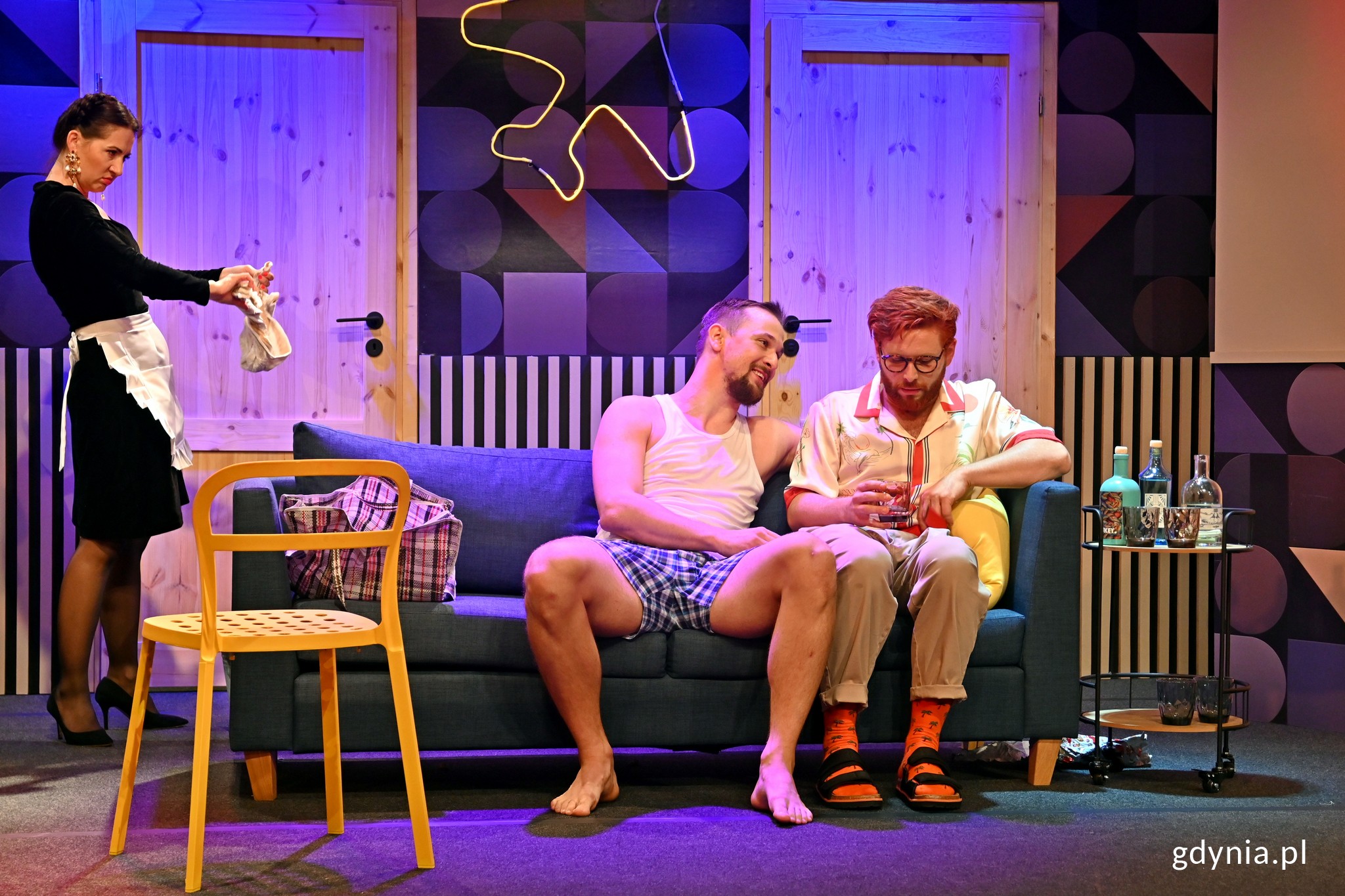 Zdjęcie z pr&oacute;by generalnej spektaklu &bdquo;Boeing Boeing&rdquo;. Po lewej stoi Sylwia Ogryzek jako Nadia. Na kanapie siedzą: Jakub Gaweł, odtw&oacute;rca roli Maksa (po lewej) i Michał Delik, kt&oacute;ry wciela się w Pawła (po prawej) // fot. Magdalena Czernek
