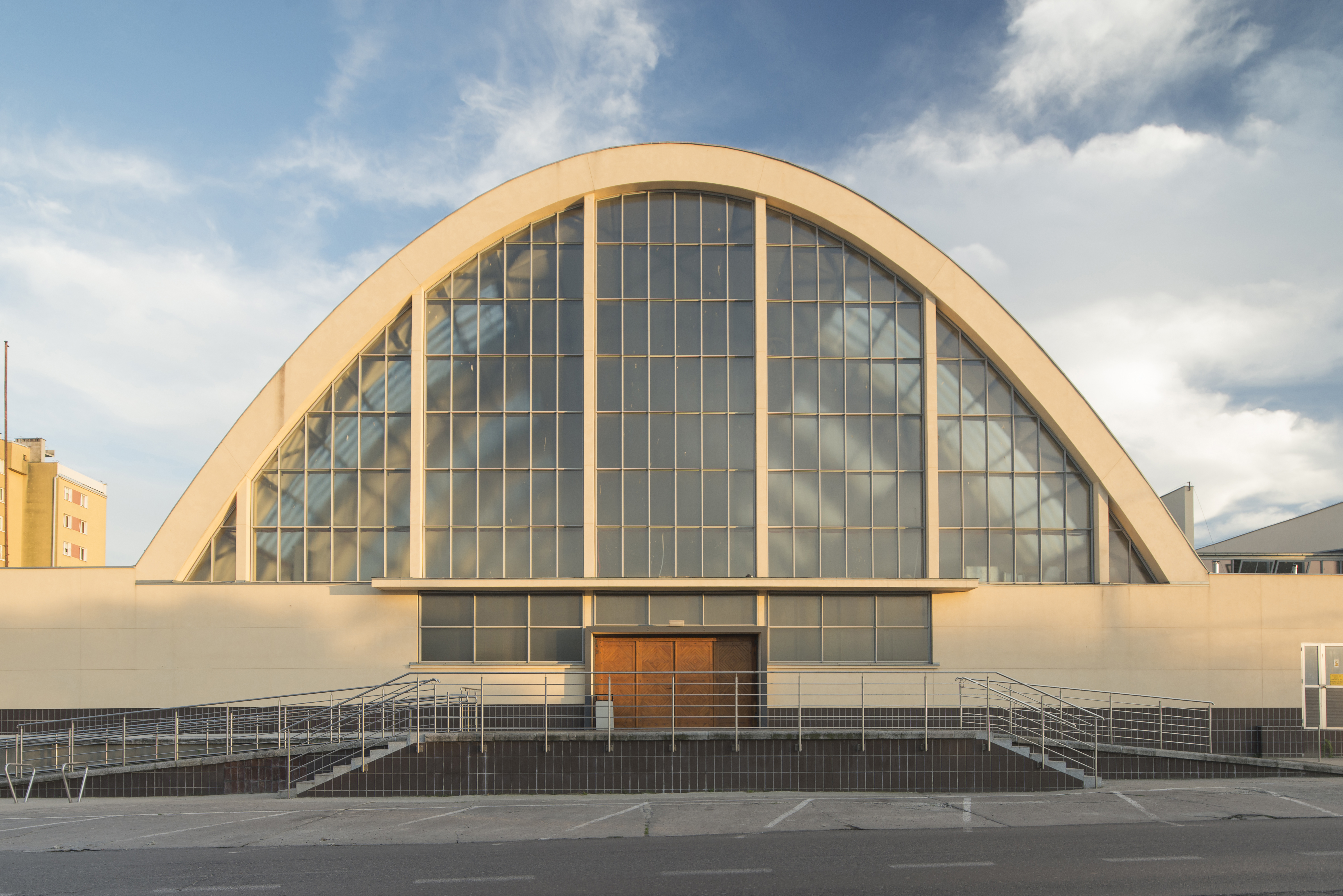 Hala targowa z lat 30. XX w. z łukami o stalowej konstrukcji, na kt&oacute;rych wykonano ż&oacute;łte tynki imitujące okładzinę z płyt kamiennych z piaskowca