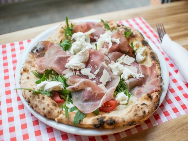 Pizza z szynką parmeńską położona na serwetce w czerwono-białą kratę. // fot. www.kulinarnagdynia.pl