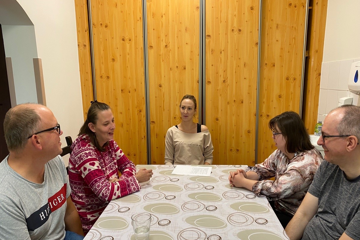 Zebrani przy jednym stole uczestnicy zajęć Środowiskowego Domu Samopomocy Maciejewicza 11 wraz z Panią psycholog, z kt&oacute;rymi rozmawiamy na temat ich opinii o zajęciach.