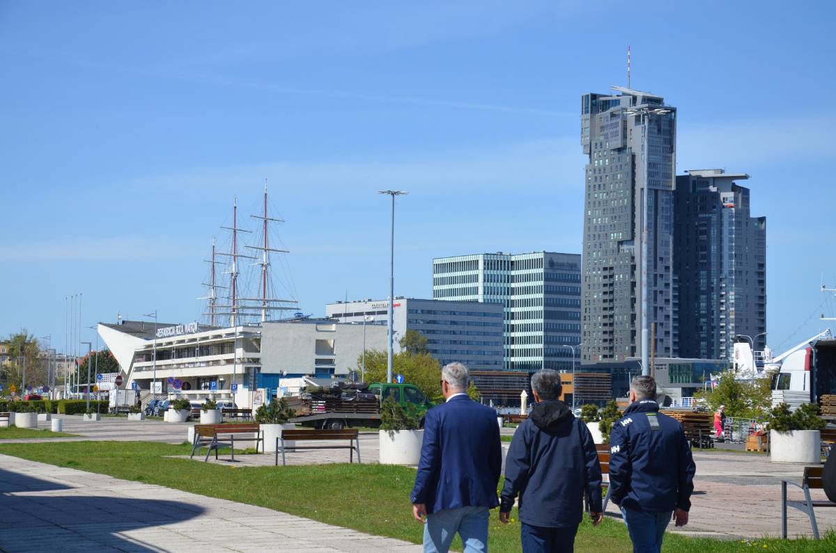 wiceprezydent WS Tomasz Chamera, prezydent WS Quanhai Li oraz dyrektor GCS Paweł Brutel zwiedzający gdyńskie nabrzeże, w tle widoczne zabudowania Gdyni i Dar Pomorza