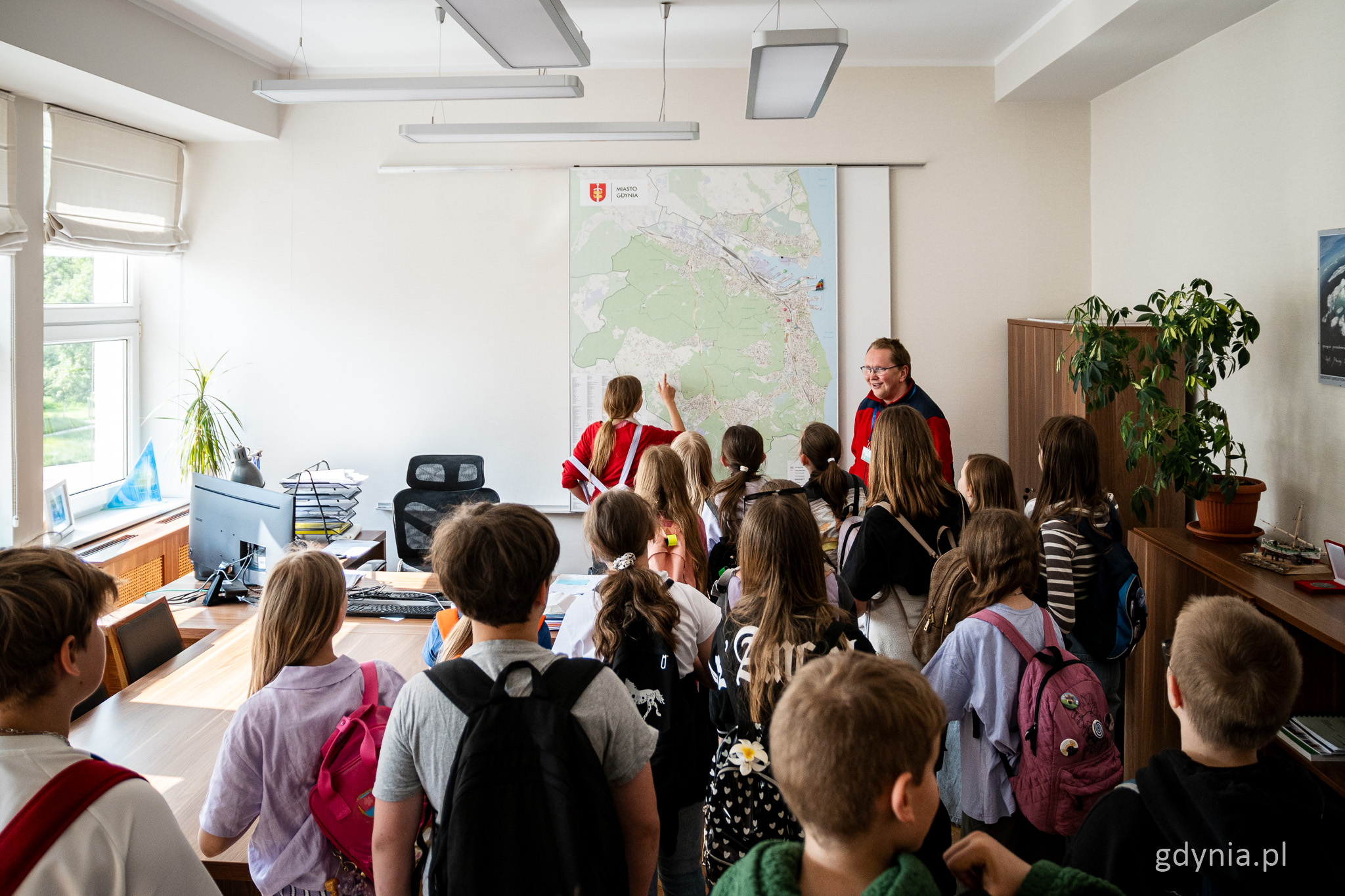 Gabinet przewodniczącego Rady Miasta Gdyni, grupa dzieci, na środku przewodnik w czerwonej kurtce