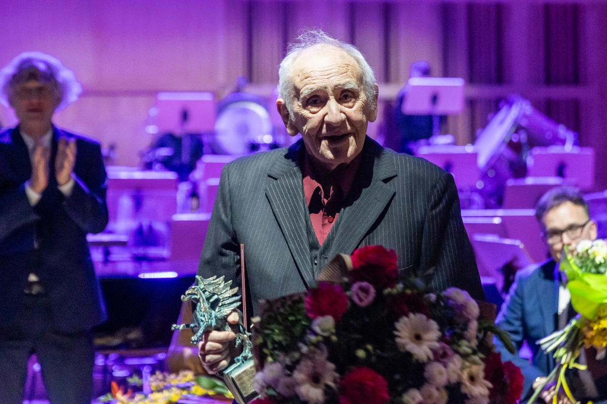 Prof. Hugon Lasecki, laureat Wielkiej Pomorskiej Nagrody Artystycznej, podczas gali. Stoi przy mikrofonie, w rękach trzyma kwiaty i statuetkę (fot. Piotr Żagiell)
