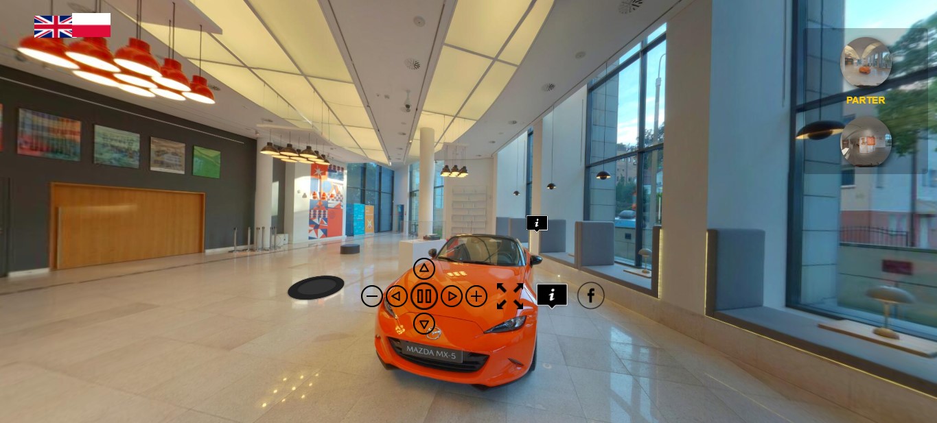 Zrzut ekranu ze strony www.kaniewski.wytworniafilmow360.pl, na kt&oacute;rej można odbyć wirtualny spacer po wystawie "Janusz Kaniewski. Polskie Projekty Polscy Projektanci". Na zdjęciu widać hol gł&oacute;wny Muzeum Miasta Gdyni i stojący po środku pomarańczowy samoch&oacute;d Mazda MX-5. Na środku widoczne są strzałki nawigujące wirtualny spacer oraz dwie flagi w lewym g&oacute;rnym rogu - brytyjska i polska - umożliwiające wyb&oacute;r języka.