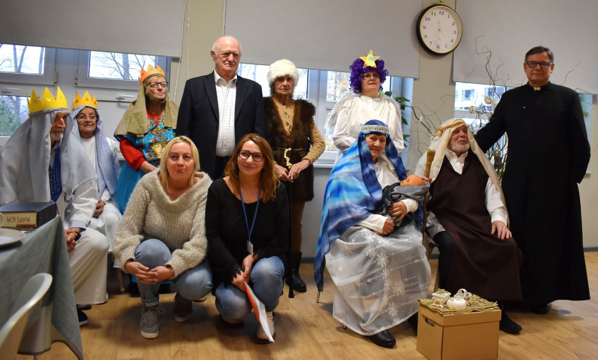 Zdjęcie przedstawia senior&oacute;w i organizator&oacute;w jasełek Dziennego Domu Senior+ w towarzystwie duszpasterza.