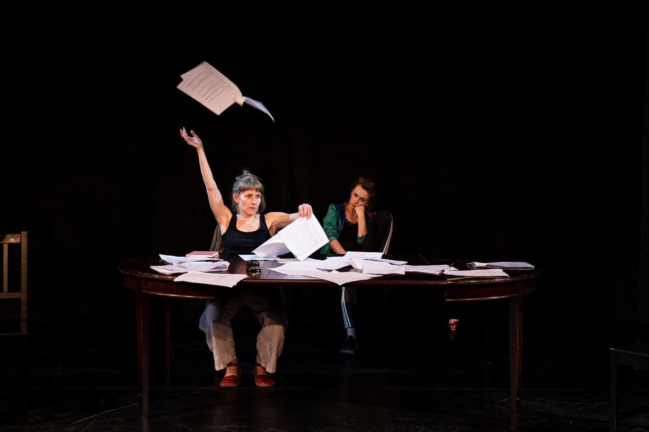 Dwie aktorki siedzą przy stole pełnym kartek