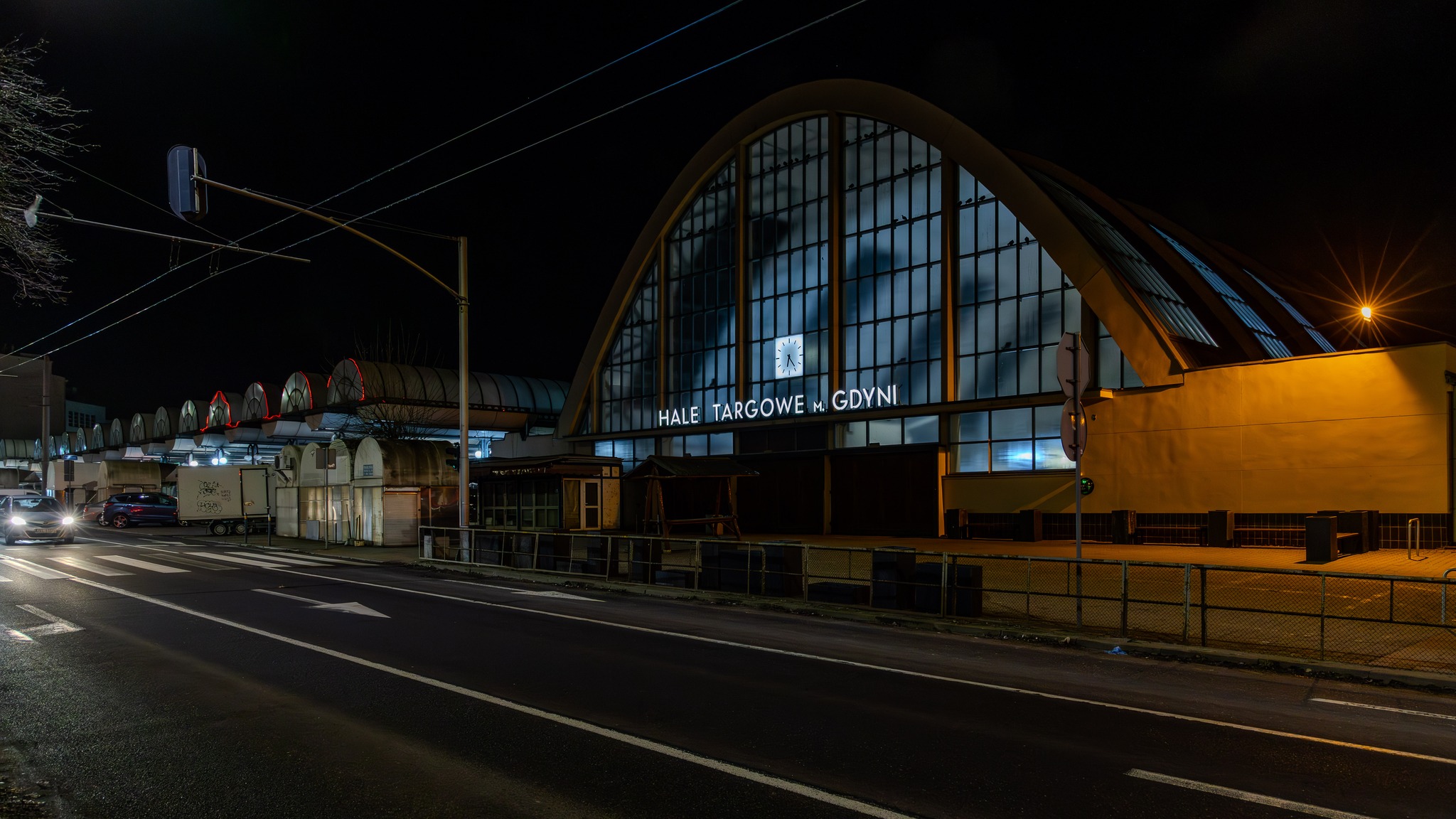 Noc, ulica, Hala Łukowa w Gdyni, widoczny podświetlony zegar na elewacji