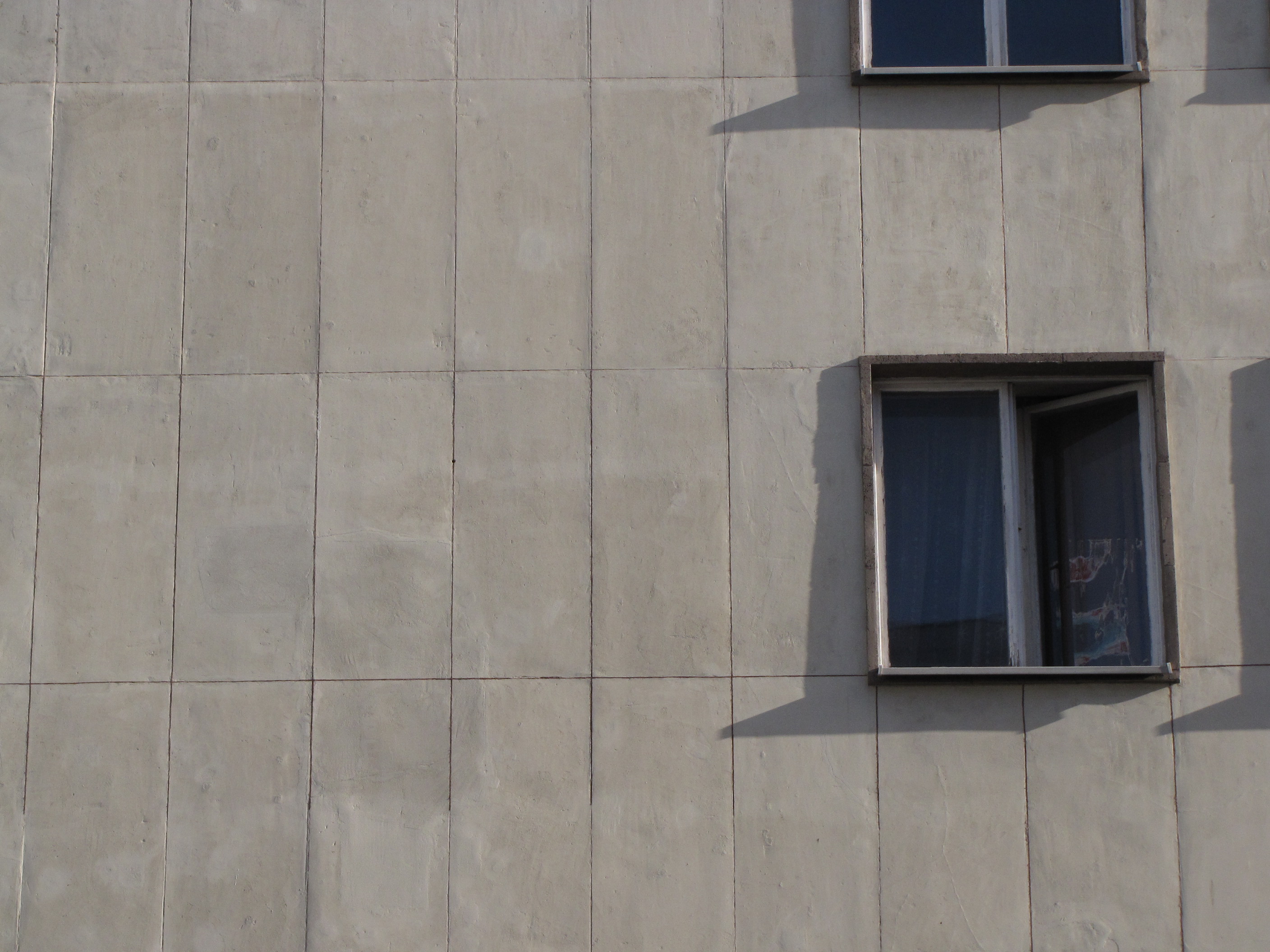 Układ płyt na elewacji budynku przy ul. 3 Maja 27-31. Każda z płyt wapienia ma grubość około 3,5 cm i waży ponad 100 kg. Wok&oacute;ł okien wykonano kamienne obramienia z porowatego trawertynu w kolorze beżowym. Płyty wapienia zostały lekko pomalowane z uwagi na liczne uszkodzenia wypełnione po wojnie zwykłą zaprawą.