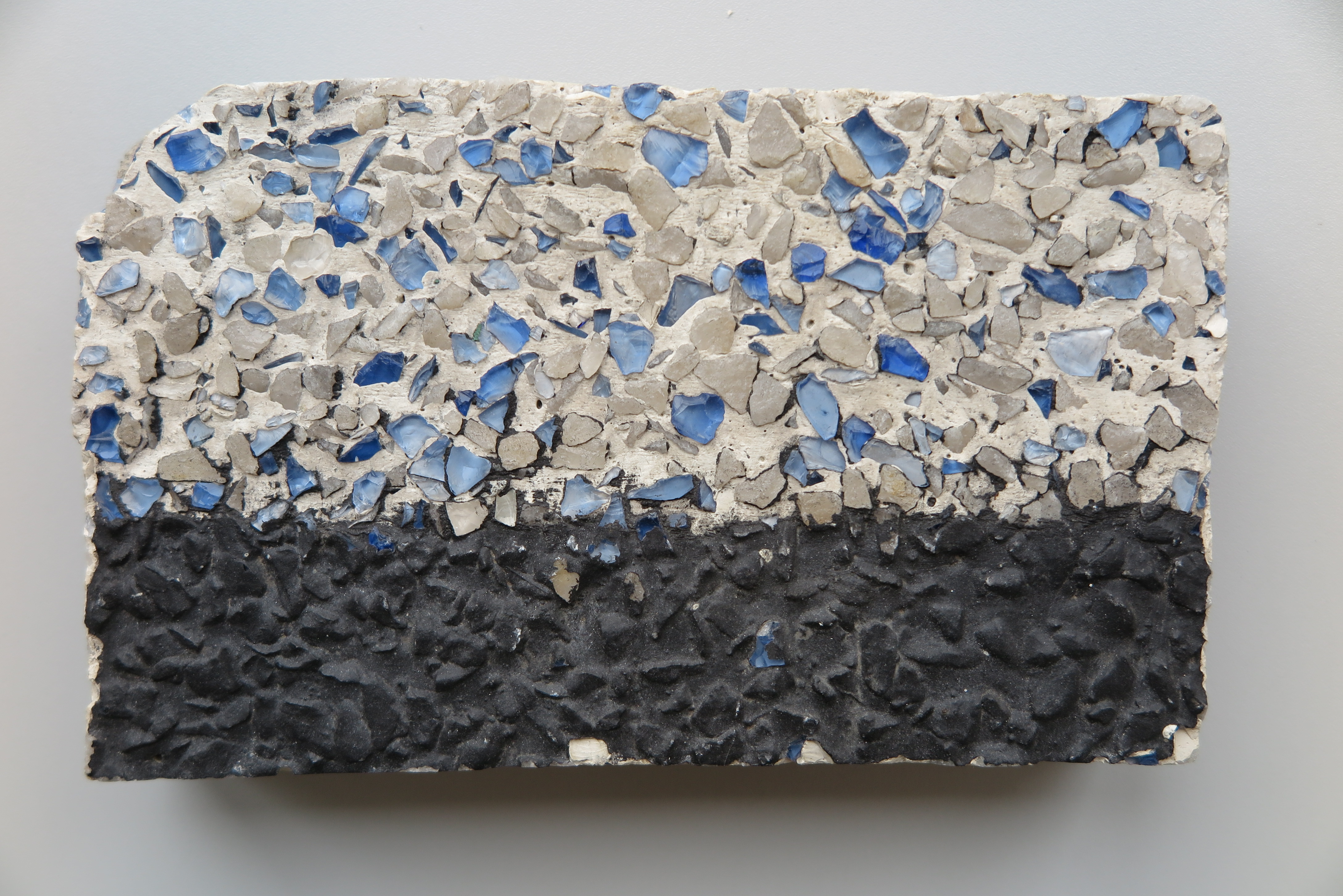 Odkryty przez konserwator&oacute;w zabytk&oacute;w na kamienicy przy ul. Świętojańskiej 37 tynk z białej zaprawy z kamykami w kolorze kremowym i okruchami niebieskiego szkła, zamalowany czarną farbą (po częściowym oczyszczeniu)