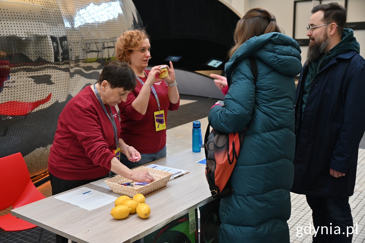 Panie z Polskiej Akcji Humanitarnej wydają parze biletu wstępu na brunch w Muzeum Emigracji