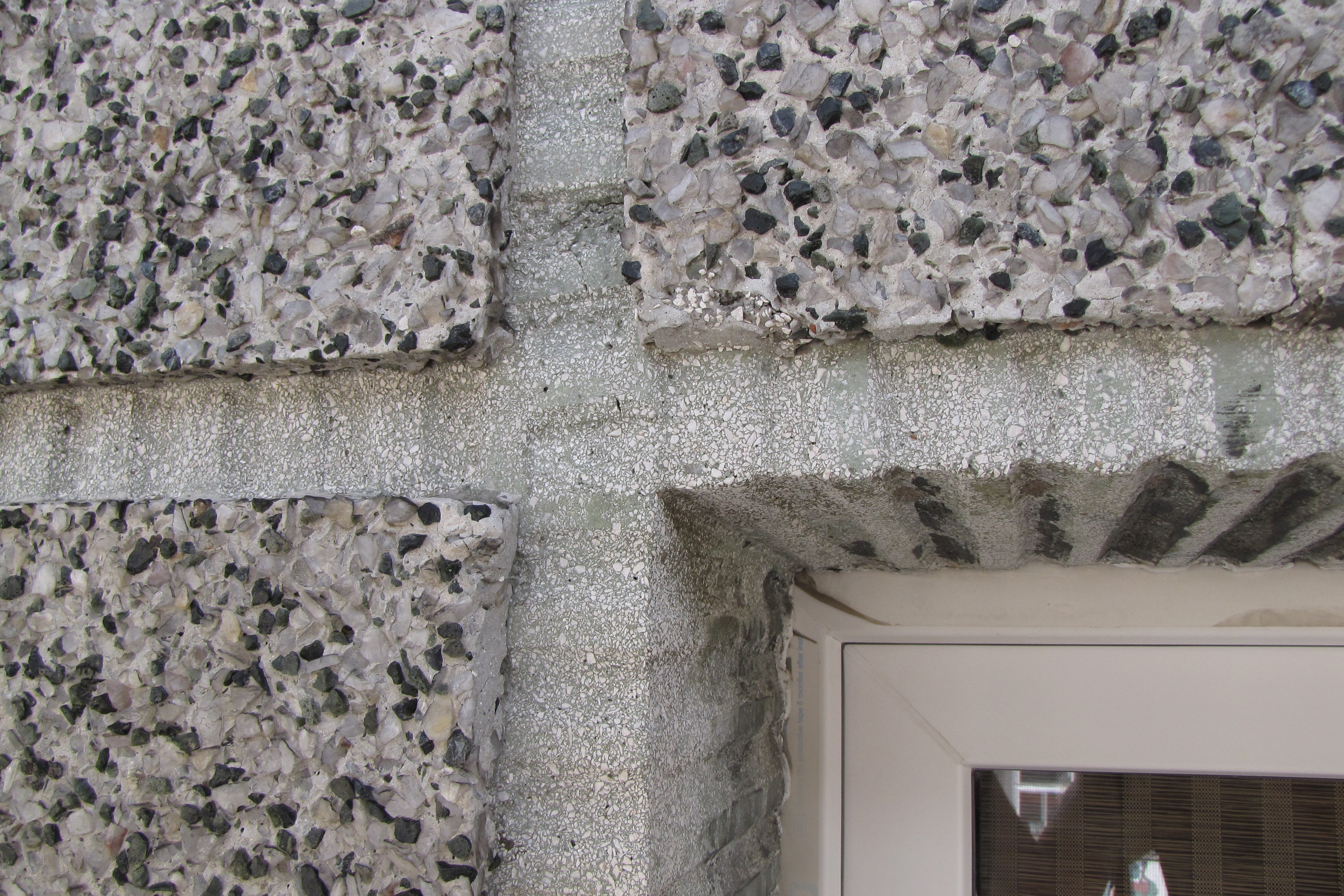Szczegół tynku z elewacji kamienicy ul. Świętojańskiej 105, z widocznymi grubymi ziarnami, które uwydatniono wypłukując zaprawę z powierzchni