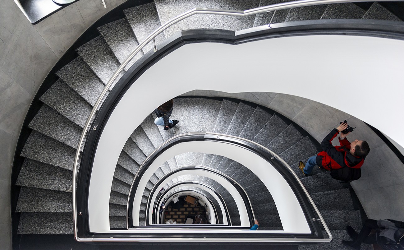 Klatka schodowa o kształcie łuku, osoby na schodach, białe ściany