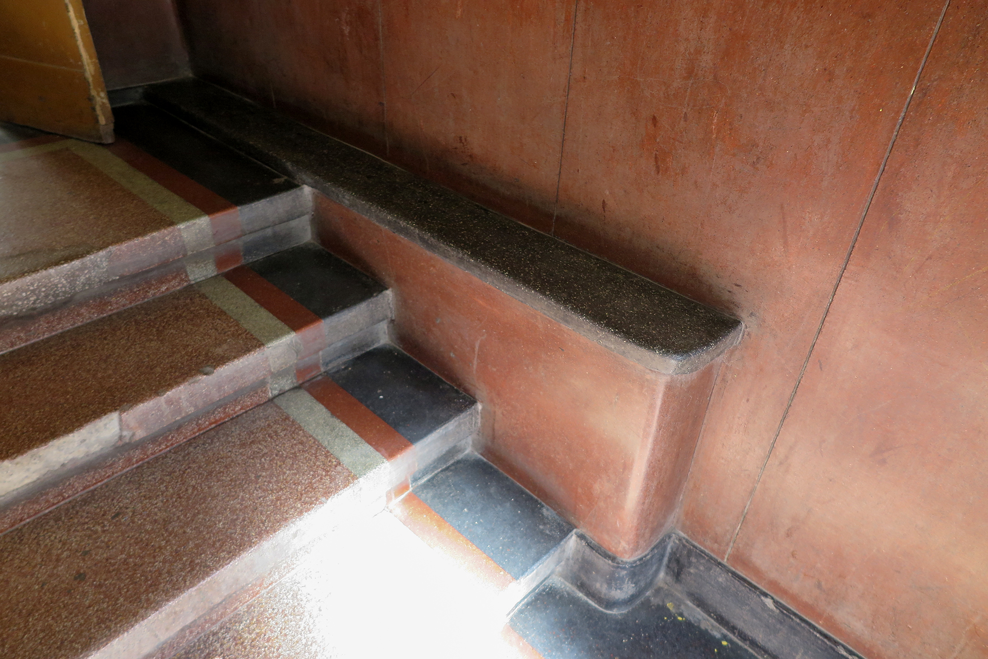 Fragment strefy wejściowej w kamienicy przy ul. Bema 15, dolne partie ścian oraz posadzka wykonana z lastryka o intensywnych kolorach.