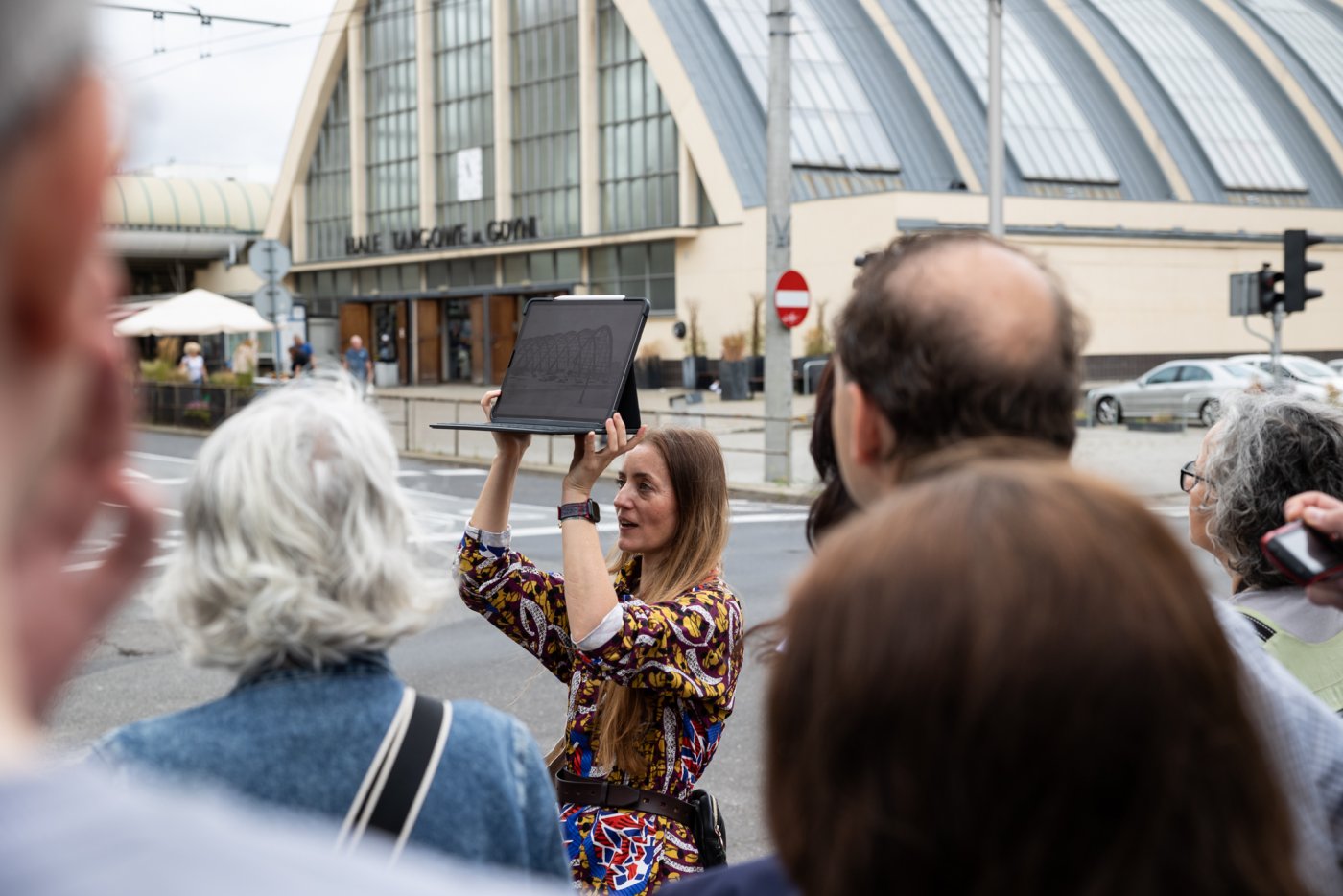 Grupa ludzi z przewodniczką, w tle gdyńska Hala Targowa