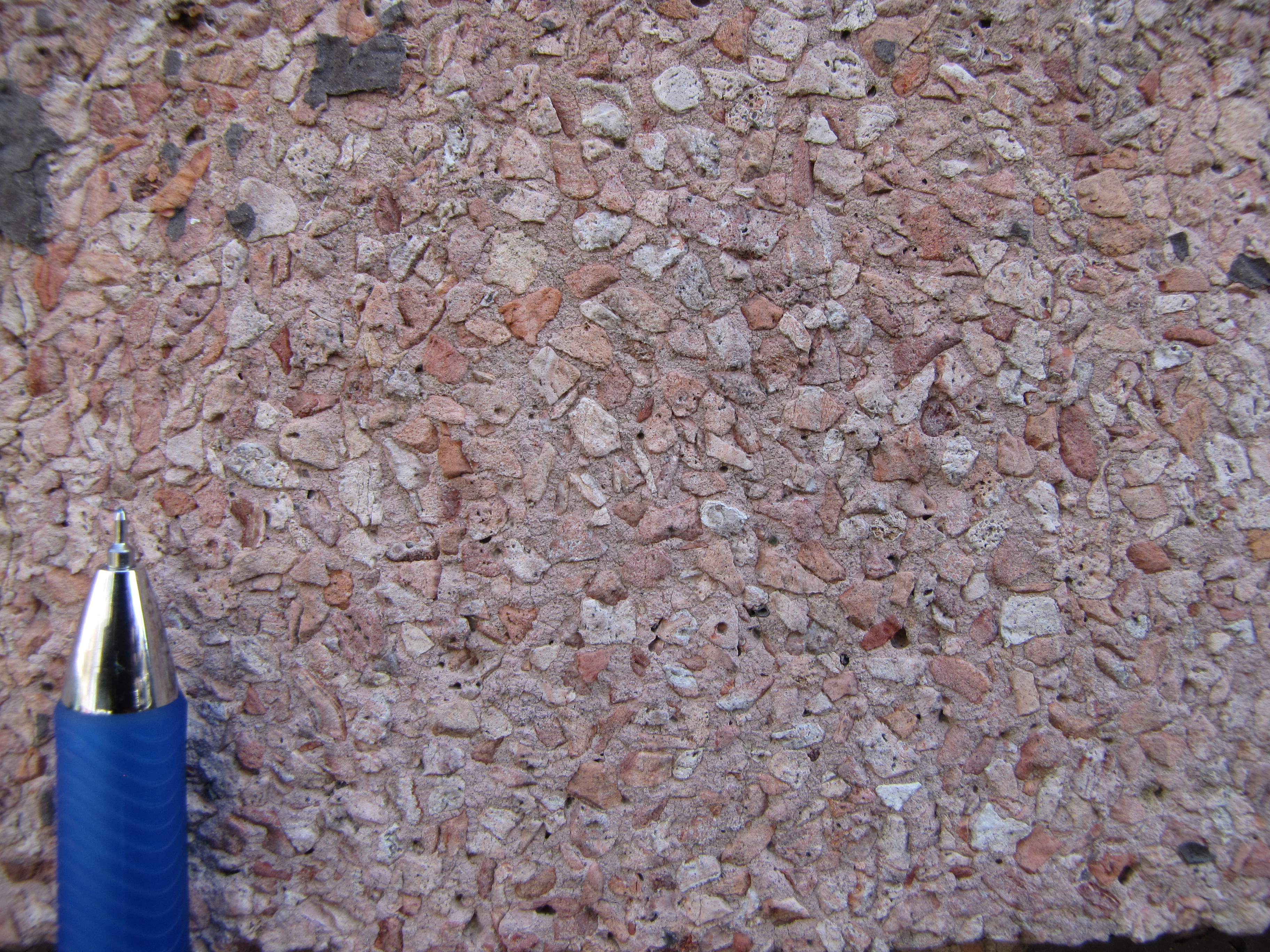 Tynk w kolorze r&oacute;żowym z ziarnami białego i r&oacute;żowego żwirku (w powiększeniu), na elewacji budynku przy ul. Bema