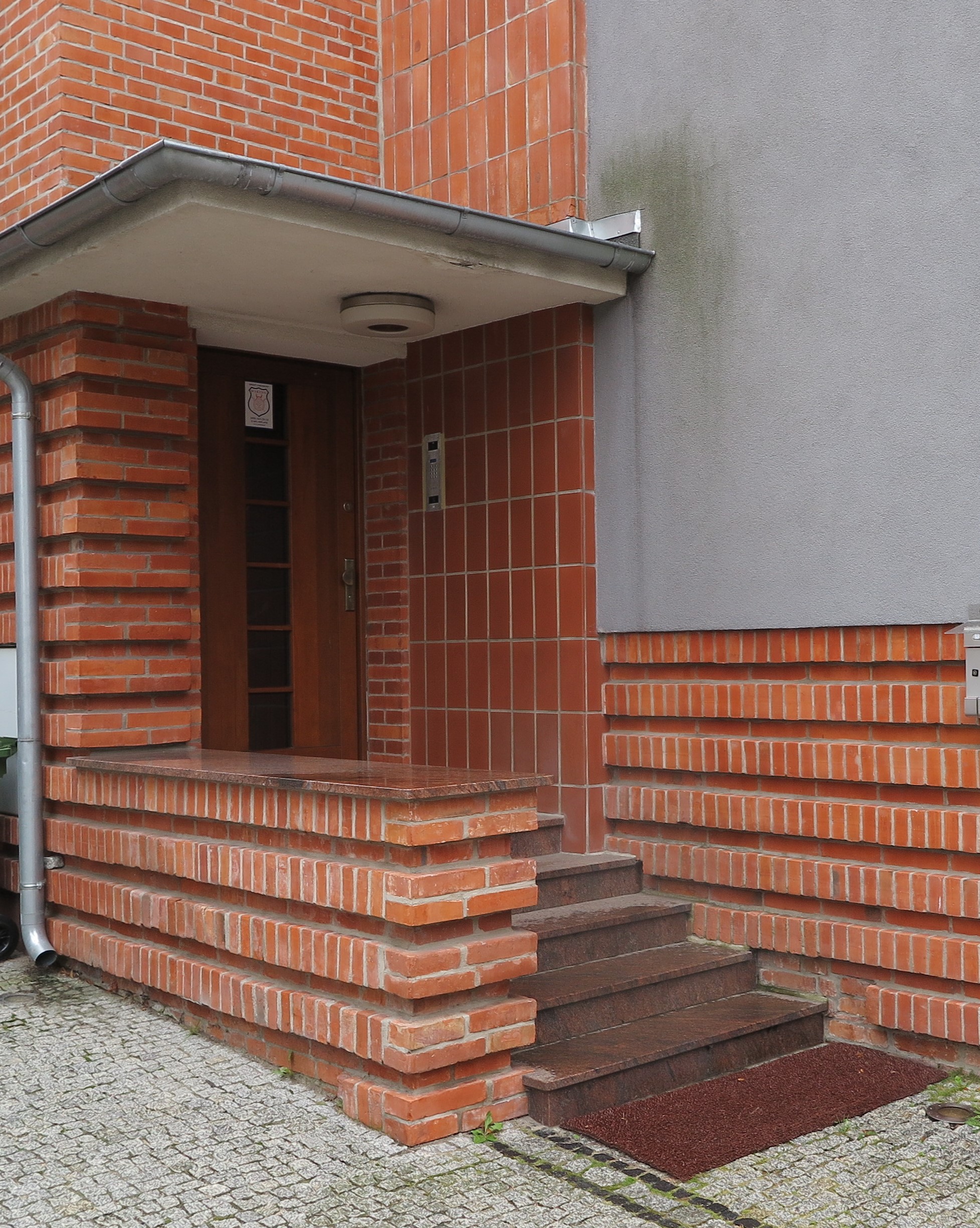 Wejście do willi modernistycznej na Kamiennej G&oacute;rze z ceglanym wykończeniem i żelbetowym daszkiem osłaniającym podest.