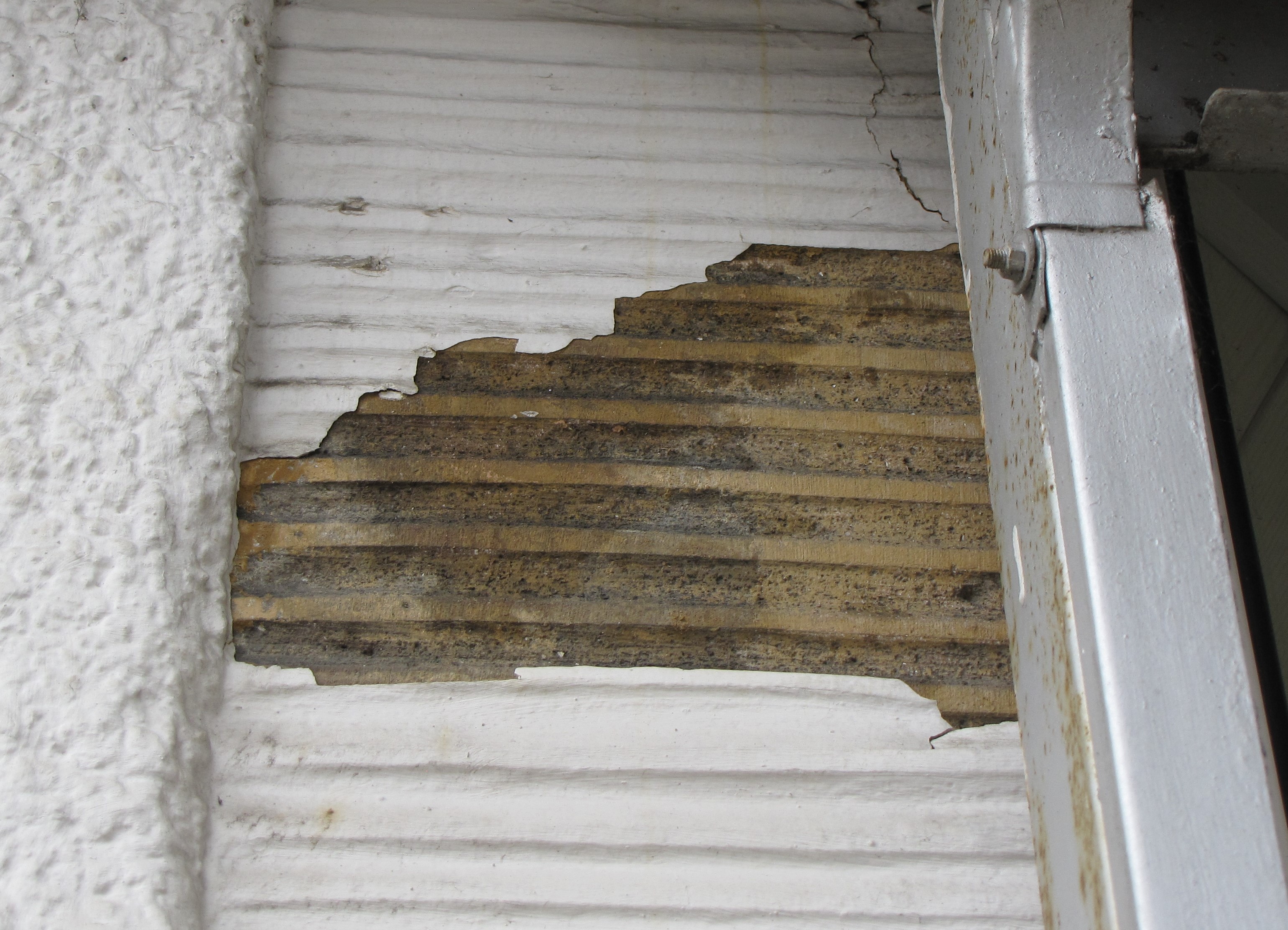 Tynk w kolorze ż&oacute;łtym z rowkami widoczny spod powojennego zamalowania białą farbą, na kamienicy przy ul. Świętojańskiej