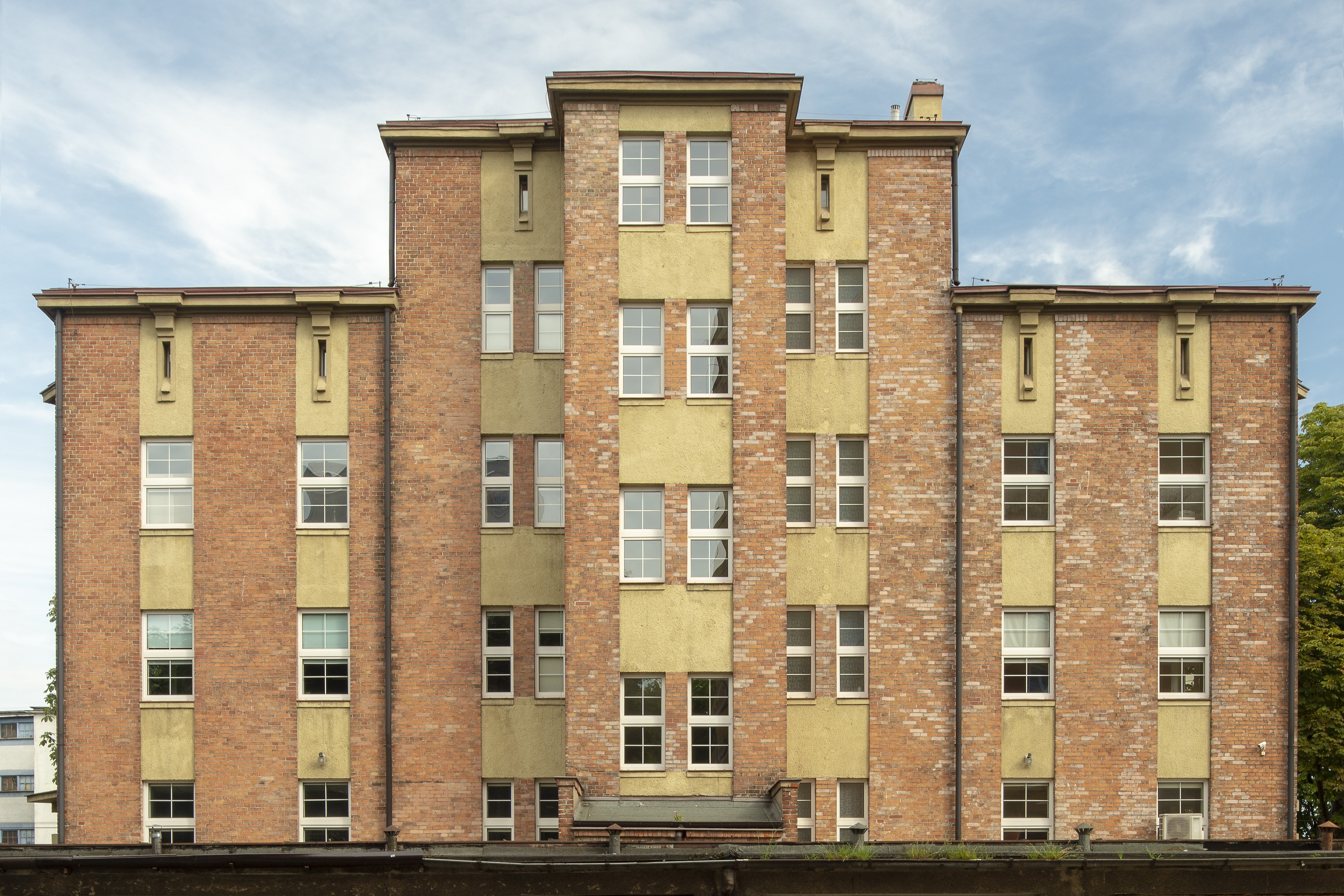 D. Dom Marynarza Polskiego, ob. Dom Rybaka przy ul. Jana z Kolna 27, kompozycja elewacji złożona z pionowych pas&oacute;w wykończonych cegłami oraz jasnym tynkiem.