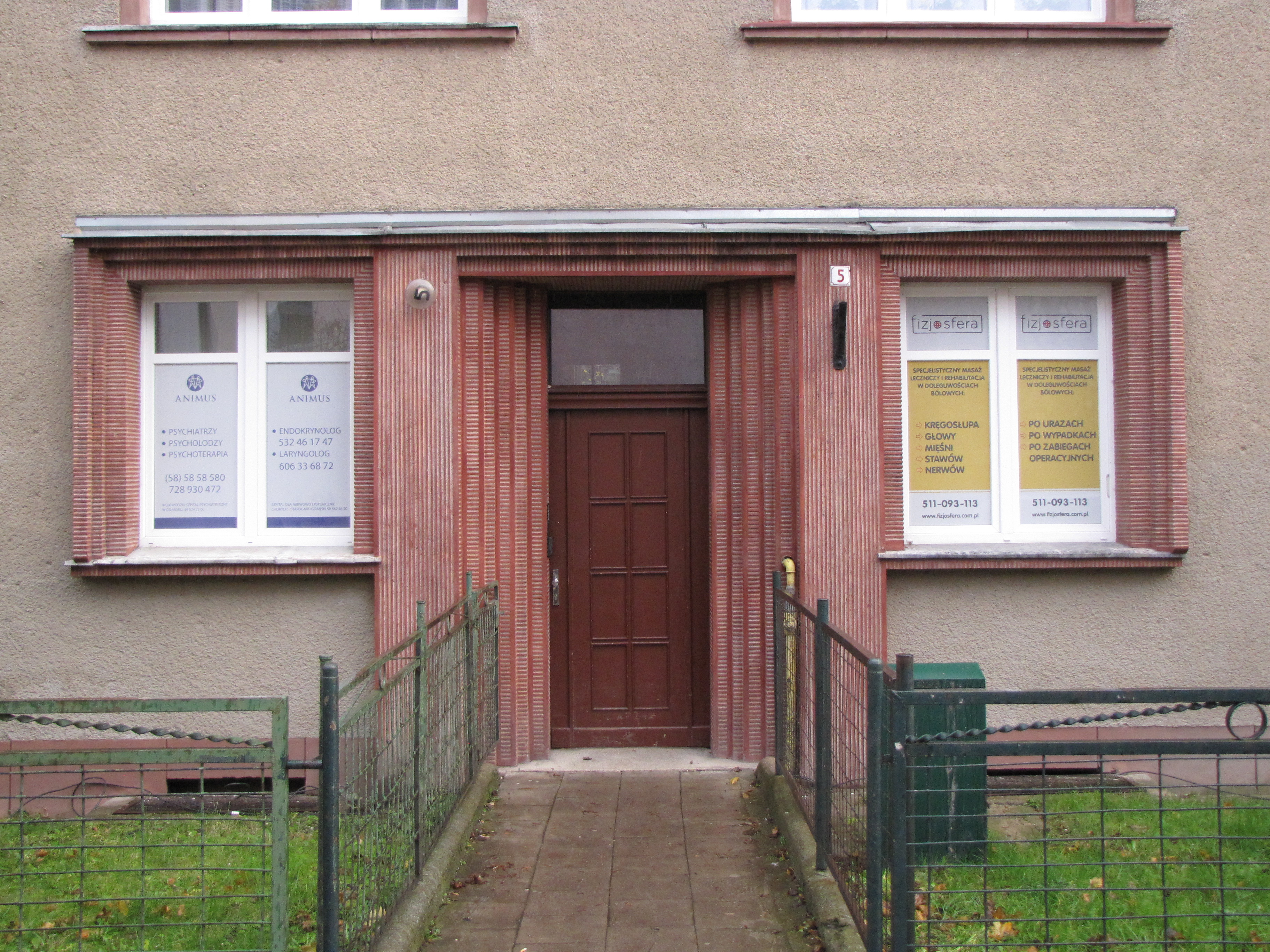 Portal kamienicy przy ul. Bema 5 z lat 30. XX w., w kt&oacute;ry włączono kompozycyjnie boczne okna, ozdobiony tynkiem szlachetnym w kolorze czerwonym.