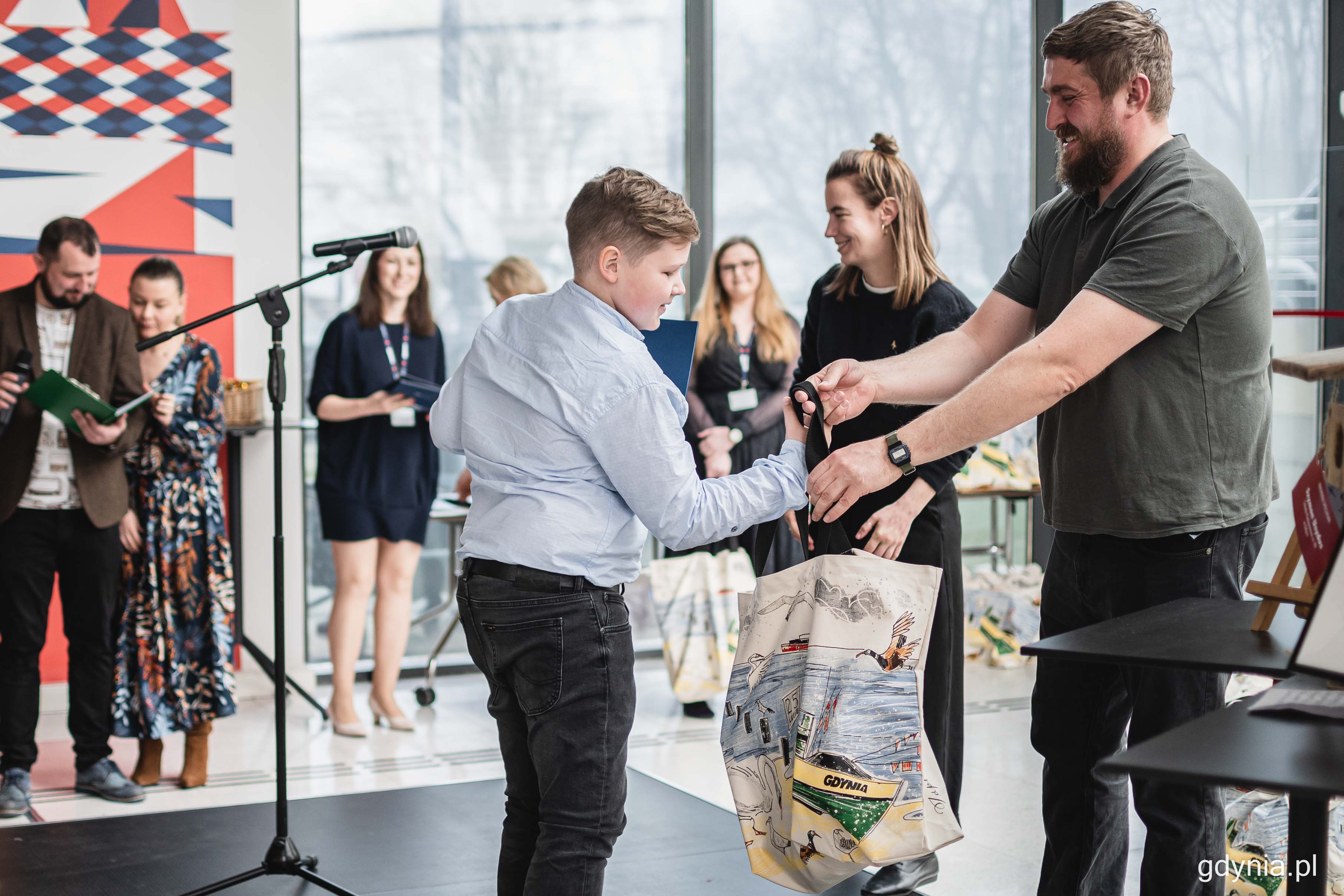 Jeden z jurorów konkursu „Zapraszamy ptaki do Gdyni”, Jakub Typiak (na zdjęciu z prawej) wręcza nagrodę jednemu z laureatów wspólnie z Zofią Różycką, autorką ilustracji związanych z akcją (na zdjęciu w środku), fot. Kamil Złoch