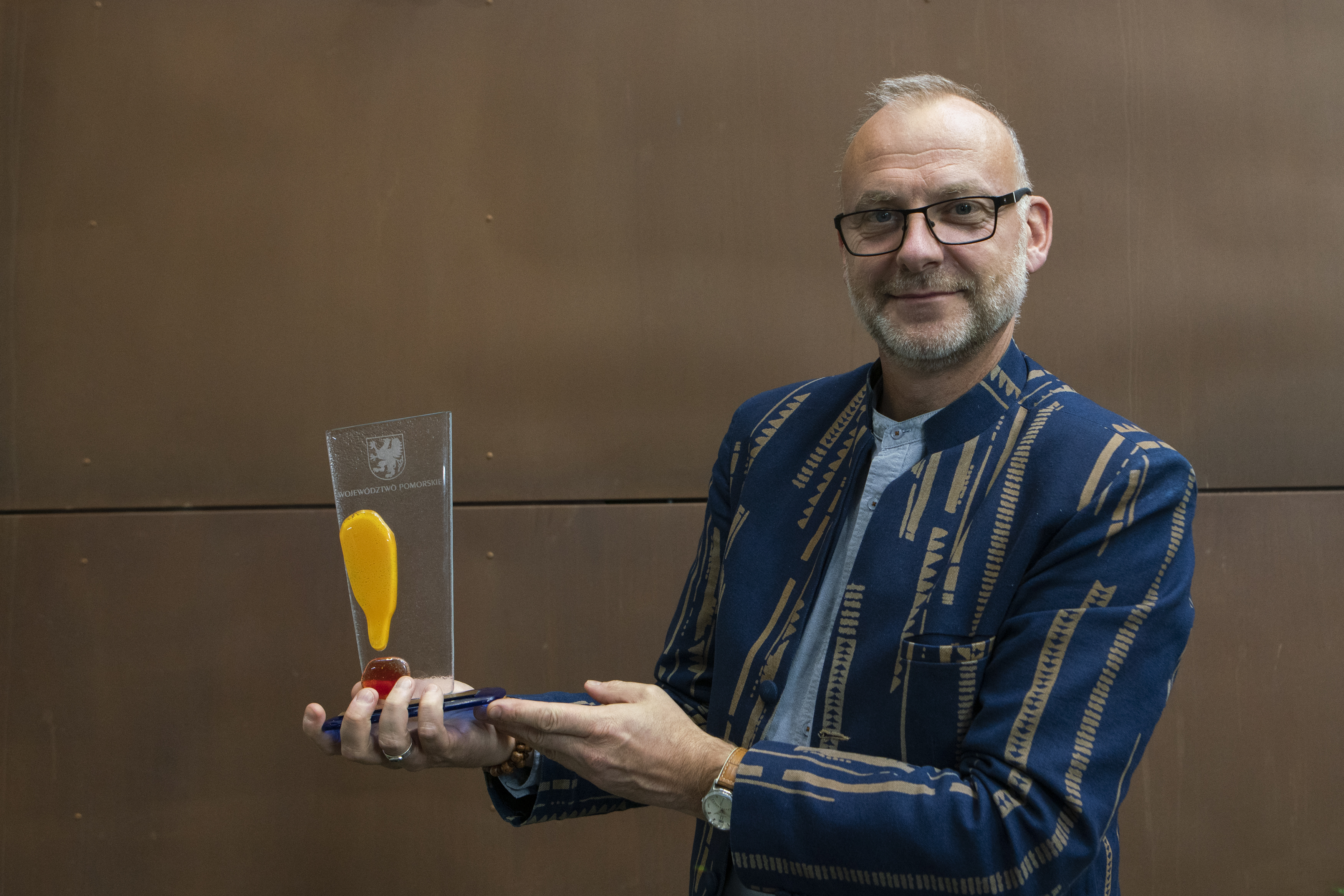 Wiceprezydent Gdyni Michał Guć trzymający w rękach nagrodę za zasługi dla rozwoju turystyki w wojew&oacute;dztwie pomorskim. 