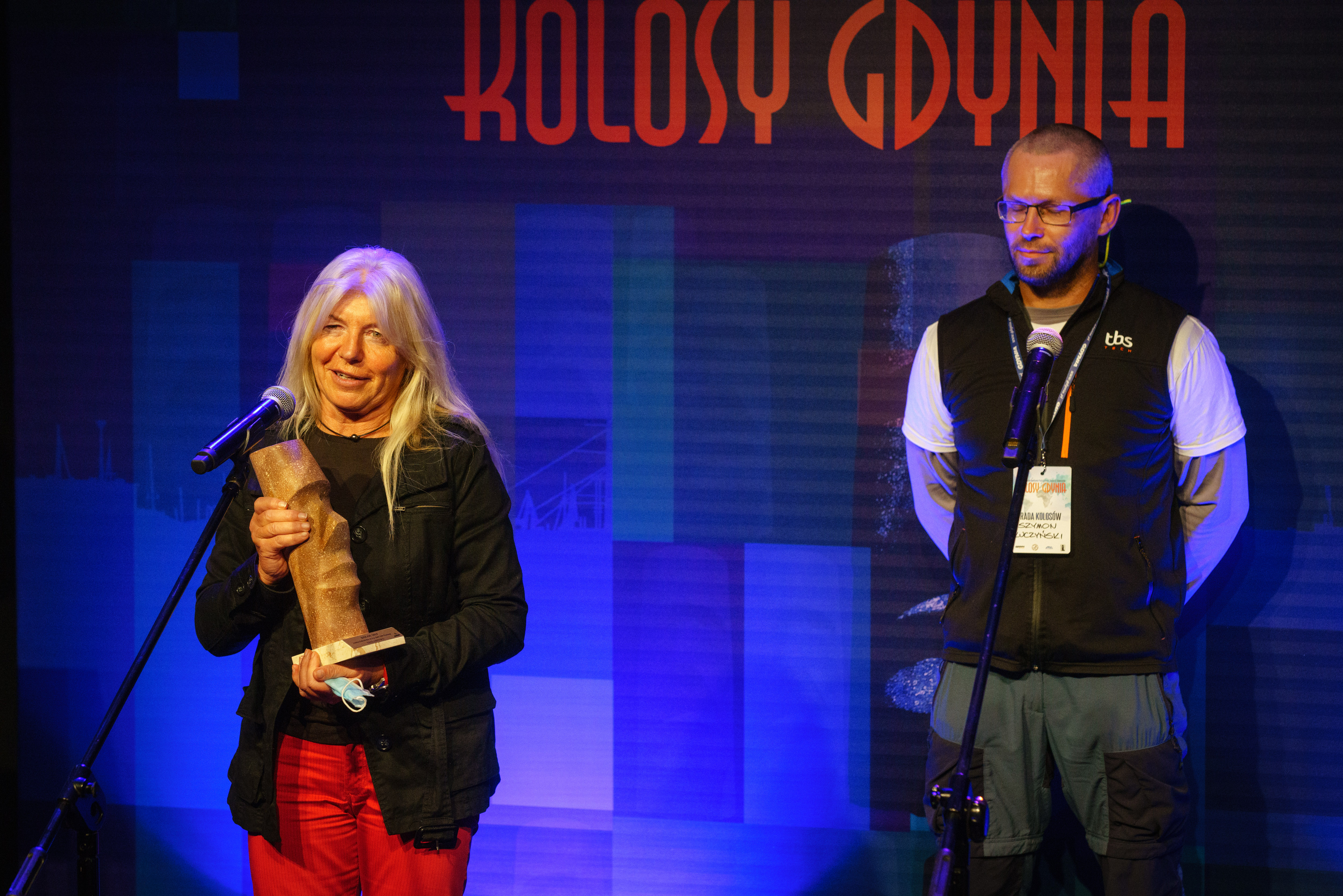 Joanna Pajkowska z Kolosem w ręku przemawia ze sceny. Z tyłu Szymon - Kuczyński - członek Rady Kolos&oacute;w // fot. Anna Rezulak