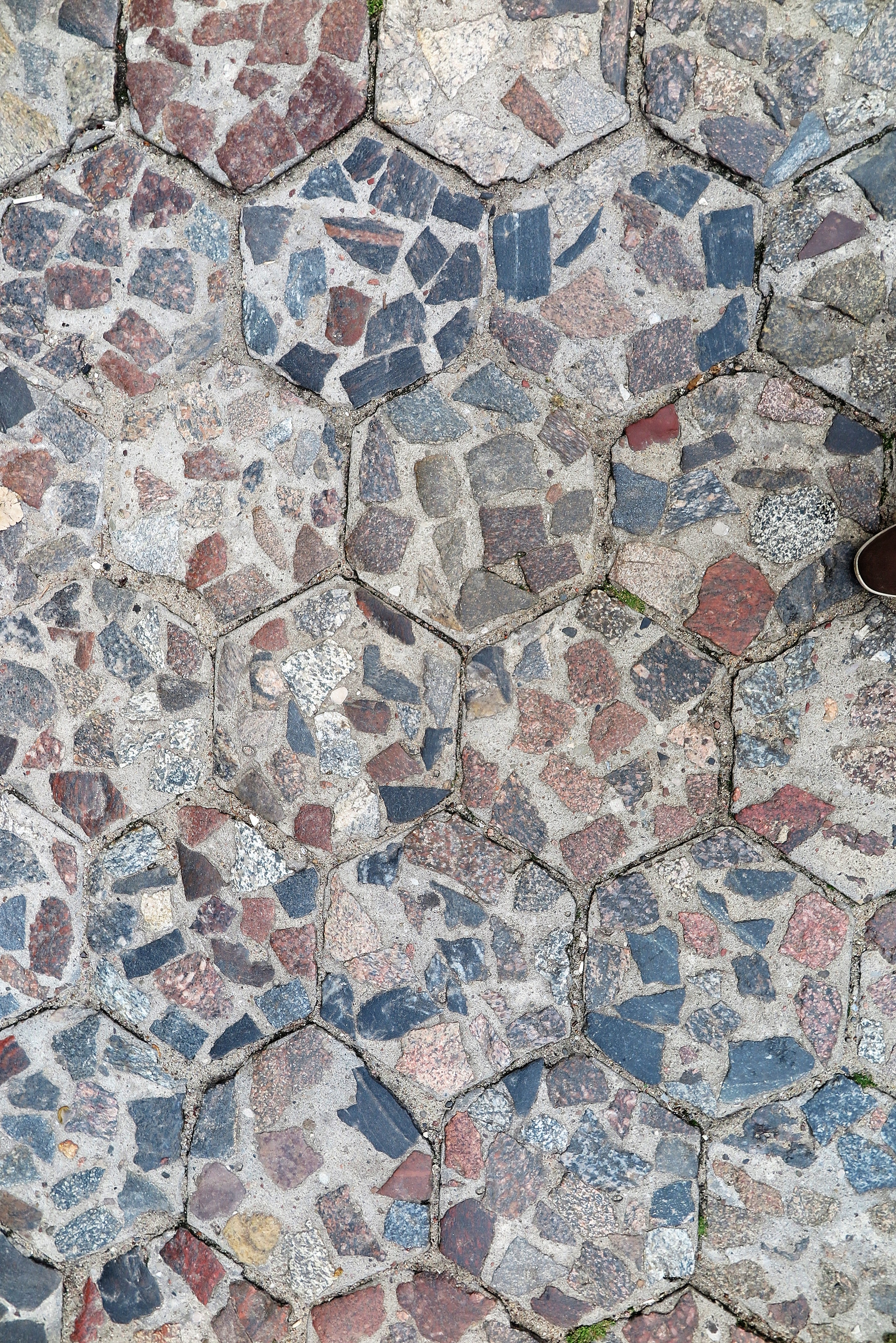 Betonowa kostka sześciokątna tzw. trylinka (od nazwiska Tryliński), z powierzchnią wyłożoną naturalnymi kamieniami, stosowana w latach 30. XX w. i po wojnie (detal)