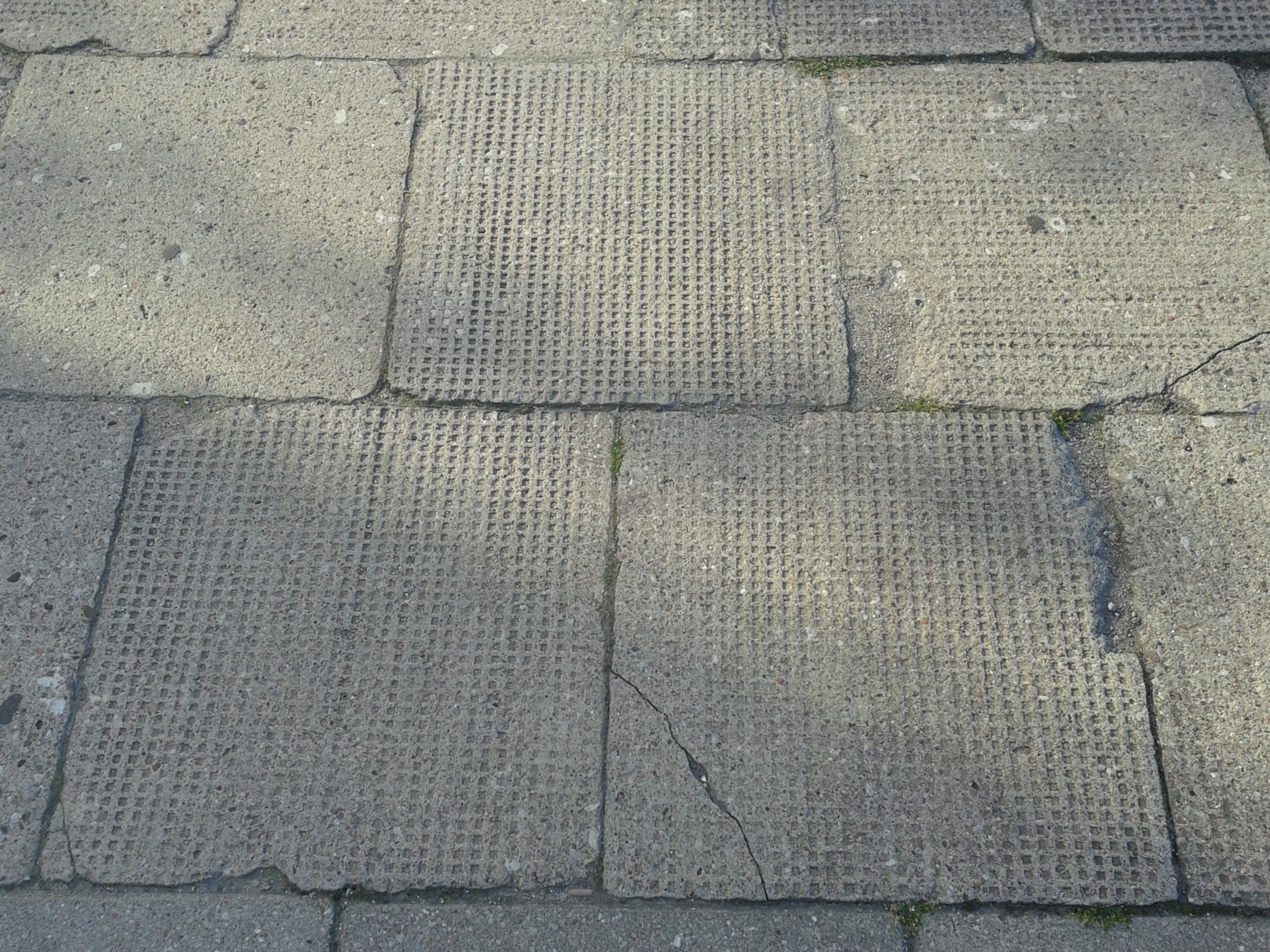 Nawierzchnia chodnika z płyt betonowych o wymiarach 50x50 cm z charakterystycznymi wgłębieniami stosowanymi w latach 30. XX w.