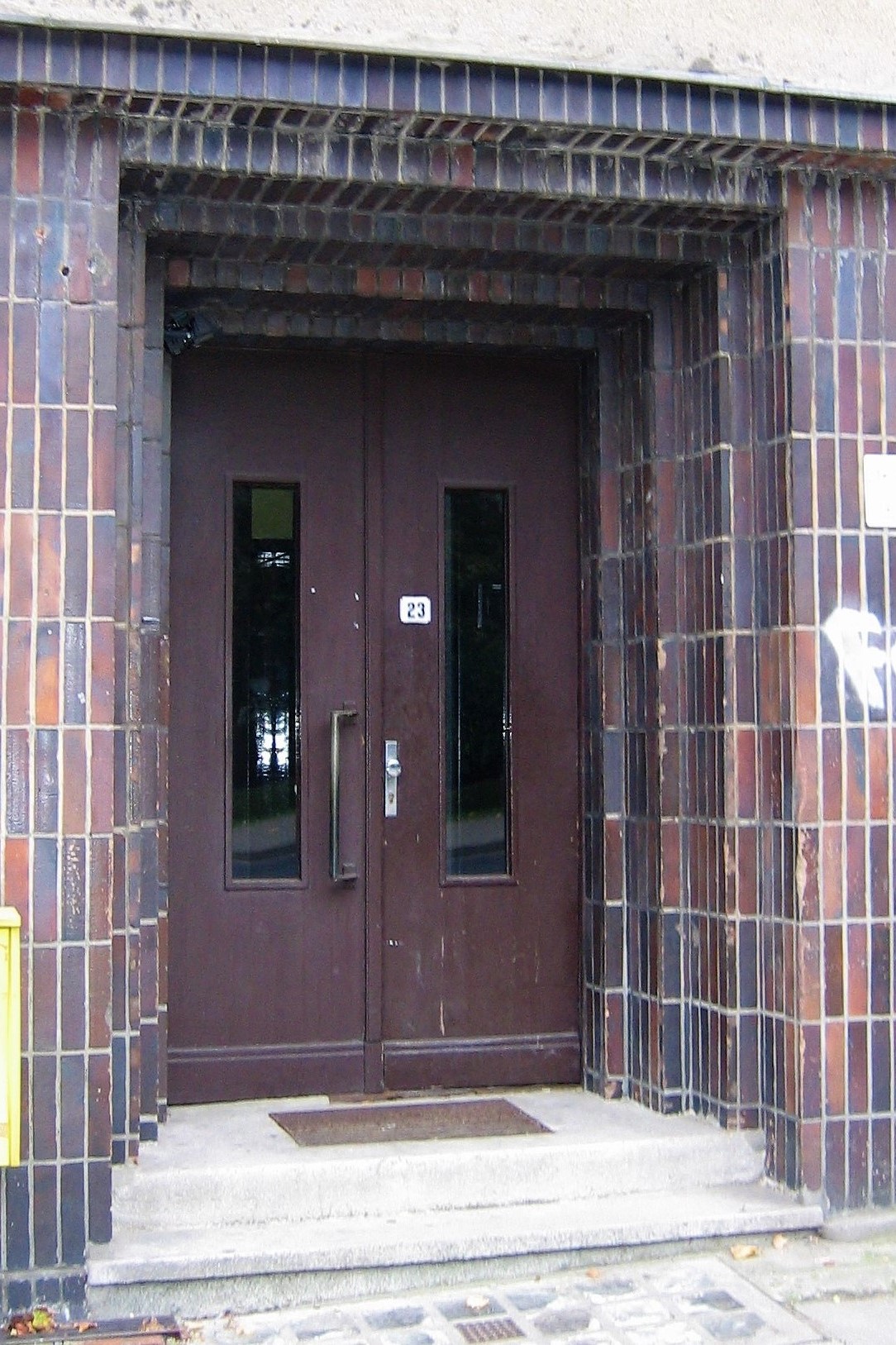 Portal części mieszkalnej budynku przy ul. Legionów, brązowymi płytkami oblicowano również elewacje pawilonu sklepowego.